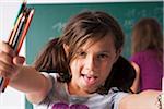 Close-up portrait of girl in classroom, holding colored pencils in hands, Germany