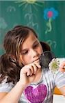 Girl in classroom examining flower with magnifying glass, Germany