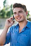 Young man using cell phone outdoors, Germany