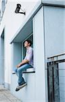 Young man sitting on ledge outdoors, Germany