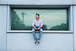 Young man sitting on ledge outdoors, Germany