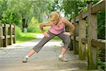 Blond woman stretching on bridge outdoors, Germany