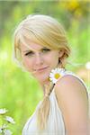 Portrait of a blond woman with a oxeye daisy flower in her hair, Germany