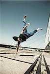 Teenaged boy doing handstand on cement road, freerunning, Germany