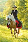 Woman Wearing Dress Riding a Connemara Stallion on a Meadow, Germany