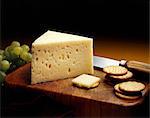 Baby Swiss Cheese Wedge on a Cutting Board with Crackers and Green Grapes