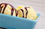 A few scoops of home-made vanilla ice cream with chocolate sauce in a bowl