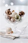 White, gold and silver Christmas tree baubles in a glass dish