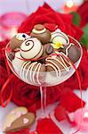 Assorted chocolate candies in a champagne glass, red roses