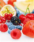 Close up of a selection of fresh fruits including blueberries, redcurrants, passion fruit, raspberries, blackberries, strawberries and cherries.