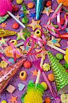 overview still life of various party decorations, party poppers sweets and straws for the party table on a purple glittery table