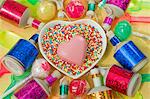 overview still life close up of heart dish with a pink chocolate heart shape and coloured party poppers and plastic ice cream spoons