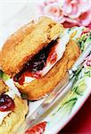 a scone filled with jam and cream on a plate with knife