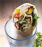 A wrap with chicken, yellow pepper, tomato, rocket, egg and cream cheese