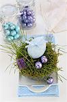 An egg decorated with a ribbon and chocolate eggs in an Easter nest made of moss and grass