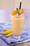 An exotic smoothie with mango and kumquats on a blue napkin on a wooden tabletop