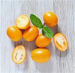 Kumquats on a wooden slab with mint, viewed from above