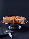 Apple and nut cake on a cake stand, with a slice cut