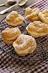 Profiteroles dusted with icing sugar, on a cooling rack