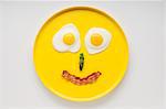 Smiley Face on a Yellow Plate Made from Two Fried Eggs, Asparagus and a Strip of Bacon