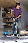 Man cleaning living room with vacuum cleaner