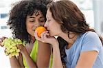 Close-up of two female friends smelling fruits