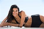 Beautiful woman in bikini lying on the beach and smiling