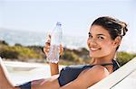 Beautiful woman holding a water bottle while sunbathing on the beach