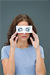 Woman hiding behind paper with false eyes