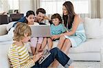 Boy using a digital tablet with his family looking at a laptop