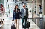 Business couple pulling suitcases in a hotel lobby