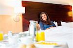 Breakfast on table in front of a woman in a hotel room