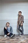 Two teenage boys leaning against a wall