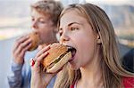 Close-up of two friends eating hamburger