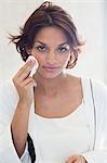 Woman cleaning her face with a cotton pad