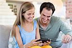 Father and daughter playing a video game and smiling at home