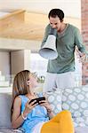 Man shouting into a megaphone at his daughter for playing video game