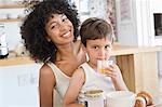 Boy drinking orange juice with his mother sitting with him