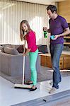 Girl cleaning floor with a mop beside her father