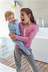 Girl carrying her brother and looking surprised in a bathroom