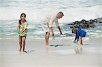 Children playing with their grandfather on the beach