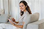 Beautiful woman using a digital tablet and smiling on a couch