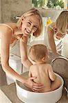 Woman giving bath to her baby in a wash bowl