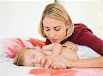 Woman looking at her baby sleeping on the bed