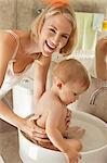 Woman giving bath to her baby in a wash bowl