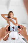 Man taking picture of his girlfriend in the bedroom