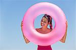 Beautiful woman looking through an inflatable ring on the beach