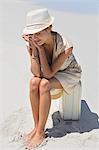 Beautiful woman sitting on a suitcase on the beach