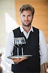 Portrait of a waiter holding a tray of wine glasses in a restaurant