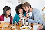 Friends sitting at a dining table and looking at a mobile phone